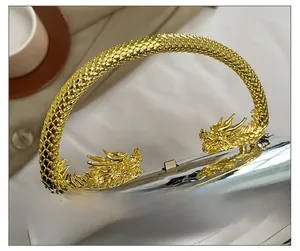 Detail of golden dragon handle on silver mirrored acrylic clutch with intricate scale texture