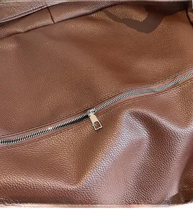 Macro shot of silver metal zipper and brown pebbled leather texture on tote bag