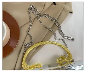 Detailed close-up of a golden dragon handle on a silver acrylic mirror evening clutch bag
