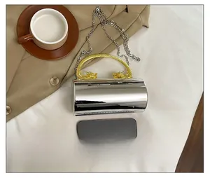 Silver cylindrical bag with a golden dragon-shaped handle and detachable metal chain strap
