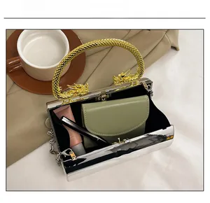Detail view of silver mirror box bag with gold dragon handles showing internal capacity