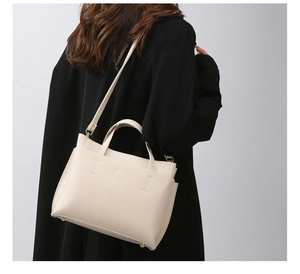 Detail of a beige tote bag showing lychee grain texture and removable shoulder strap