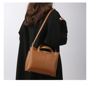 Detail of brown lychee texture tote bag with geometric design and metal bottom rivets