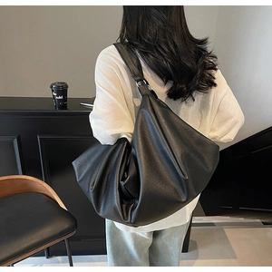 Close-up of a large black leather tote bag with pebble texture and slouchy design