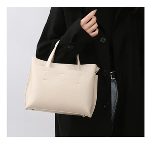 Close-up of cream leather tote bag with IOI stitching and protective metal feet