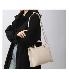 Detail of minimalist cream tote bag featuring embossed geometric pattern and leather straps