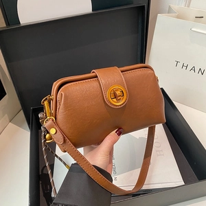 Brown leather handbag with gold circular lock and shoulder strap on premium gift packaging