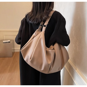 Close-up of beige lychee grain leather texture and pleated design on tote bag