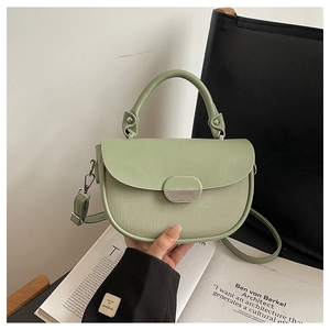 Sage green patchwork saddle bag with silver buckle shown in a lifestyle hand-held setting