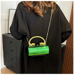 Detail of emerald green cylinder bag with golden dragon handle and chain strap