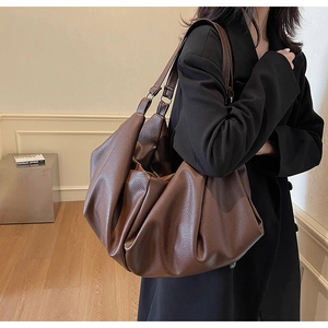 Detail of dark coffee tote bag featuring lychee grain texture and slouchy pleated design