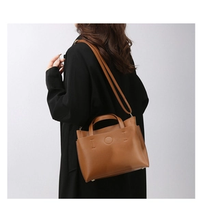 Detail of a brown lychee pattern tote bag with IOI embossing and adjustable shoulder strap