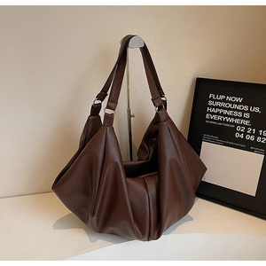 Detail of soft dark brown leather tote bag with lychee texture and pleated design