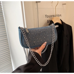 Blue denim underarm bag with silver rivets and chunky chain strap on a black blazer