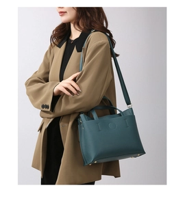 Detail of dark green tote bag with lychee grain texture and metal bottom protective studs