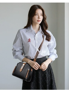 Detail of black lychee grain leather bucket bag with brown trim and silver twist lock