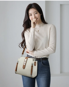 Detail view of cream bucket bag with brown leather straps and metal twist lock closure