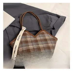 Detail of plaid tote bag with brown leather handles and 'Chia 2nd' ribbon strap