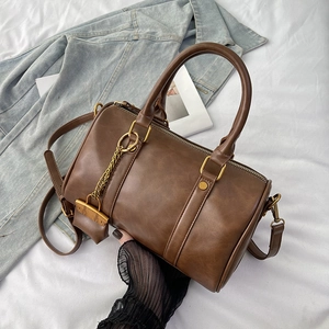 Retro brown Boston handbag with double handles and adjustable strap on denim background