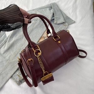 Classic wine red Boston handbag with gold chain detail on a denim background