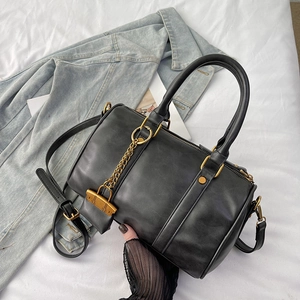 Retro black Boston handbag with gold chain detail and mini pouch on white fabric background
