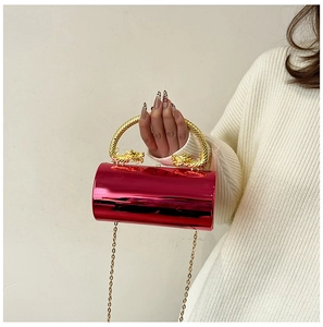 Close-up of red cylindrical evening bag with gold dragon-shaped handles and chain strap