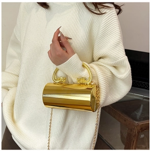 Detail of gold mirror evening clutch featuring ornate dual dragon handles and chain