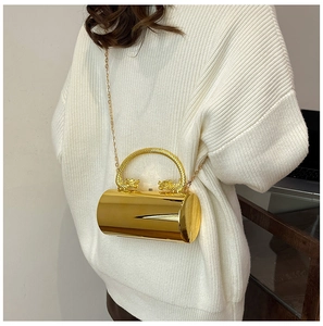 Detail of gold cylindrical clutch bag featuring unique twin dragon head handles and chain