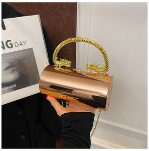 Macro detail of rose gold cylindrical clutch with ornate gold dragon-shaped handles