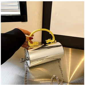 Detail of silver cylindrical evening bag featuring a gold dragon handle and metal chain