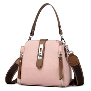 Pink faux leather bucket bag with brown handles and a wide shoulder strap in a 3/4 view