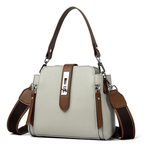 Minimalist beige leather bucket bag with brown handles and a wide shoulder strap