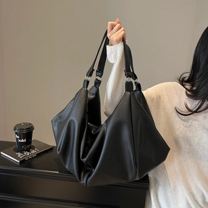 Minimalist black pebbled leather tote bag with silver rings shown in a lifestyle setting