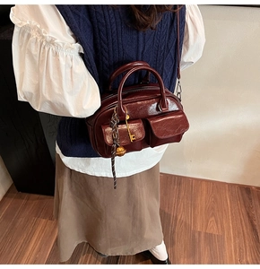 Detail of vintage burgundy glossy handbag featuring front pockets and key pendant