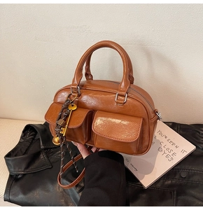 Detail view of vintage brown PU leather handbag with front flap pockets and key charm