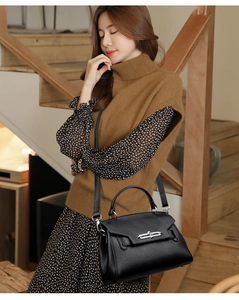 Detailed view of black litchi pattern leather handbag with silver lock and shoulder strap