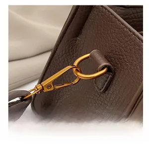 Détail du sac à main en cuir grainé marron foncé avec crochet en métal doré mat poli