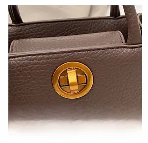 Détail du cuir grainé de qualité et du fermoir rotatif doré sur un sac à main
