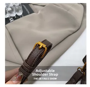 Détail de la bandoulière réglable en cuir marron foncé avec boucle en métal doré poli