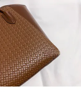Dettaglio della borsa tote in pelle intrecciata marrone scuro con trama fitta artigianale