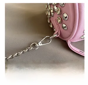 Detail of pink leather cylinder bag with silver studs and metal lobster clasp attachment