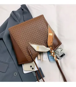 Dettaglio di una borsa tote marrone intrecciata con foulard di seta e interno capiente