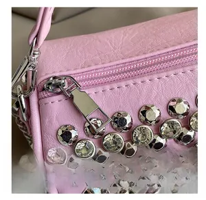 Close-up of smooth metal zipper and sparkling rhinestone details on pink cylinder bag