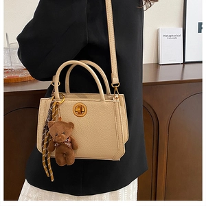 Détail d'un sac cabas beige grainé avec fermoir doré et pendentif ours en peluche