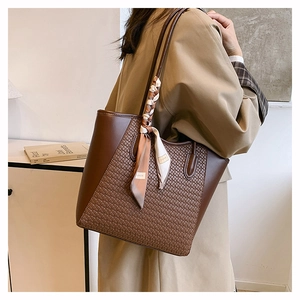 Dettaglio della grande borsa tote intrecciata marrone con foulard decorativo sul manico