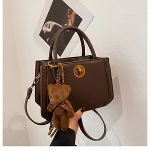 Détail du sac en cuir marron avec fermoir tournant doré et charm ours en peluche