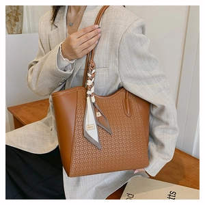 Dettaglio di una grande borsa tote marrone con trama intrecciata e foulard in seta sul manico