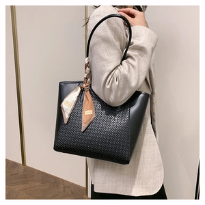 Dettaglio borsa tote in pelle nera con trama intrecciata e foulard decorativo chic