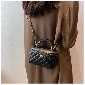 Classic black quilted crossbody bag with gold flower detail worn with a brown coat