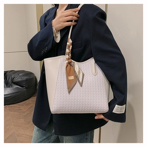 Dettaglio della borsa tote crema con trama a intreccio, manici in pelle e foulard